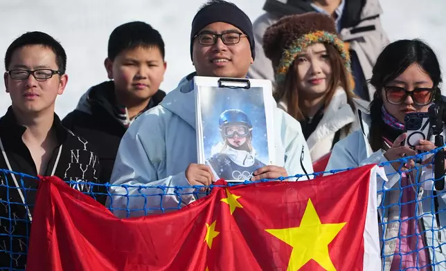 A fan holds a photo of China's Eileen Gu before the women's freestyle skiing halfpipe final at the 2026 Winter Olympics, in Livigno, Italy, Sunday, Feb. 22, 2026. (AP Photo/Lindsey Wasson)