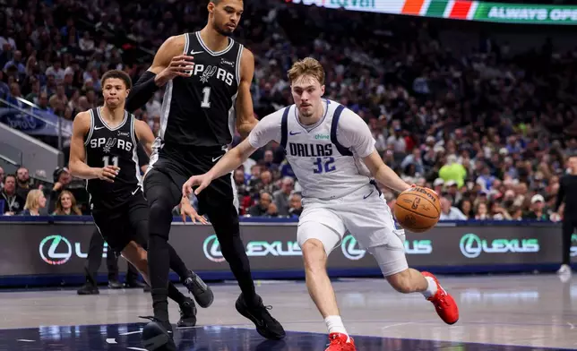 Dallas Mavericks forward Cooper Flagg (32) drives to the basket against San Antonio Spurs forward Victor Wembanyama (1) in the first half of an NBA basketball game, Thursday, Feb. 5, 2026, in Dallas. (AP Photo/Gareth Patterson)