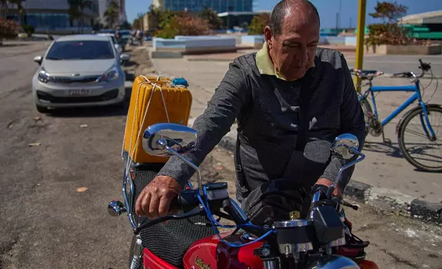 Retiree Jorge Reyes pushes his motorcycle to refuel as it's his turn in line at a gasoline station in Havana, Cuba, Monday, Feb. 16, 2026. (AP Photo/Ramon Espinosa)
