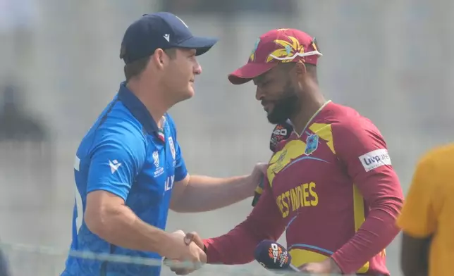 West Indies' captain Shai Hope right, shake hands with Italy's captain Wayne Madsen before the start of the T20 World Cup cricket match between West Indies and Italy in Kolkata, India, Thursday, Feb. 19, 2026. (AP Photo/Bikas Das)