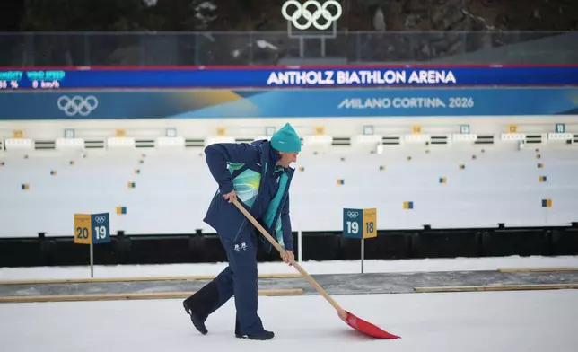 A worker shovels at the biathlon venue ahead of the 2026 Winter Olympics in Anterselva, Italy, Thursday, Feb. 5, 2026. (AP Photo/Andrew Medichini)