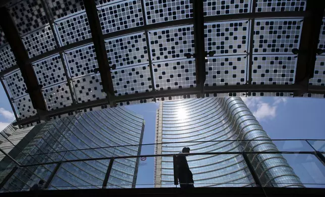 FILE - A man walks in the Porta Nuova urban district in Milan, Italy, on April 22, 2016. (AP Photo/Luca Bruno, File)