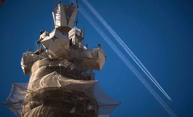 A crane lifts the upper arm of the cross onto the Tower of Jesus Christ at the Sagrada Familia in Barcelona, Spain, Friday, Feb. 20, 2026, reaching the basilica's maximum height of 172.5 meters (566 feet). (AP Photo/Emilio Morenatti)