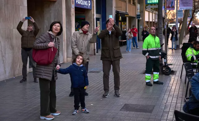 People watch as a crane lifts the upper arm of the cross onto the Tower of Jesus Christ at the Sagrada Familia in Barcelona, Spain, Friday, Feb. 20, 2026, reaching the basilica's maximum height of 172.5 meters (566 feet). (AP Photo/Emilio Morenatti)