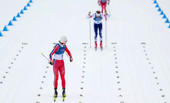 Gold medalist Johannes Hoesflot Klaebo, left, of Norway, looks back at silver medalist Ben Ogden, of the United States, and bronze medalist Oskar Opstad Vike, also of Norway, when approaching the finish line in the cross-country skiing men's sprint classic at the 2026 Winter Olympics, in Tesero, Italy, Tuesday, Feb. 10, 2026. (AP Photo/Matthias Schrader)