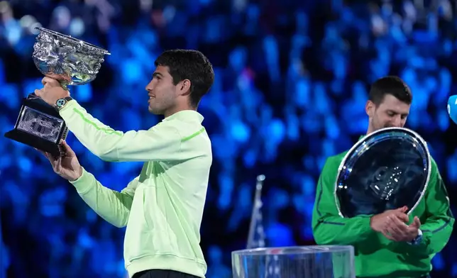 Carlos Alcaraz, left, of Spain holds the Norman Brookes Challenge Cup after defeating Novak Djokovic of Serbia in the men's singles final at the Australian Open tennis championship in Melbourne, Australia, Sunday, Feb. 1, 2026. (AP Photo/Aaron Favila)