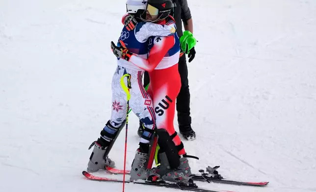 Norway's Henrik Kristoffersen, left, hugs Switzerland's Loic Meillard at the finish area, during an alpine ski, men's slalom race, at the 2026 Winter Olympics, in Bormio, Italy, Monday, Feb. 16, 2026. (AP Photo/John Locher)