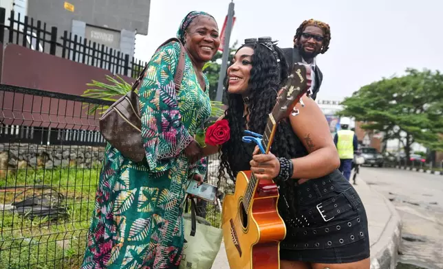 Nigerian rock musician Bianca "Clayrocksu" Okorocha, accompanied by Daniel Onyemachi-Chiweolu, popularly known as Machigold, hugs a woman after giving her a single-stem rose and crooning love songs ahead of Valentine's Day in Lagos, Nigeria, Tuesday, Feb.10, 2026. (AP Photo/Sunday Alamba)
