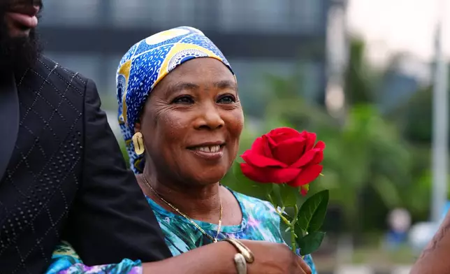 A woman reacts after receiving a single-stem rose from Nigerian rock musician Bianca "Clayrocksu" Okorocha ahead of Valentine's Day on a street in Lagos, Nigeria, Tuesday, Feb.10, 2026. (AP Photo/Sunday Alamba)