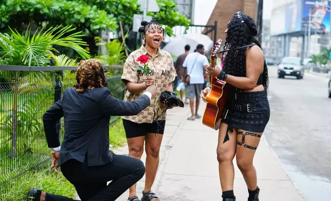 Nigerian rock musician Bianca "Clayrocksu" Okorocha, right, accompanied by Daniel Onyemachi-Chiweolu, popularly known as Machigold, left, gives single-stem roses crooning love songs to commuters ahead of Valentine's Day in Lagos, Nigeria, Tuesday, Feb.10, 2026. (AP Photo/Sunday Alamba)