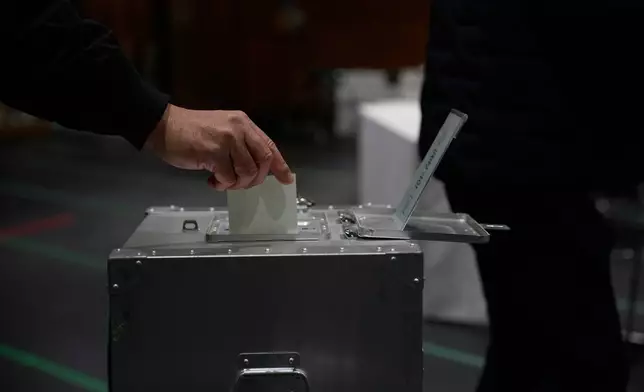 A voter casts a ballot in the upper house election at a polling station Sunday, Feb. 8, 2026, in Tokyo. (AP Photo/Louise Delmotte)