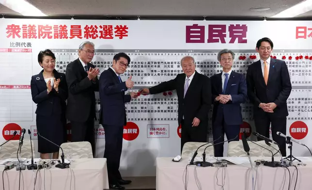 Japan's ruling Liberal Democratic Party (LDP) Secretary-General Shunichi Suzuki and other lawmakers puts pins marking the names of candidates who won lower house elections at the LDP headquarters in Tokyo, Sunday Feb. 8, 2026. (Kim Kyung-Hoon/Pool Photo via AP)