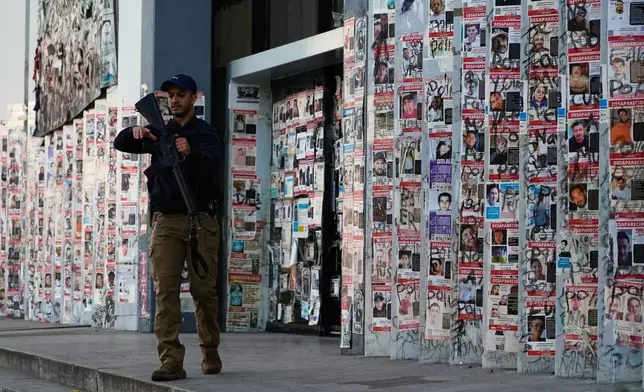 A police officer walks past posters of missing persons in front of the Special Prosecutor's Office for Missing Persons in Guadalajara, Mexico, Wednesday, Feb. 25, 2026. (AP Photo/Marco Ugarte)