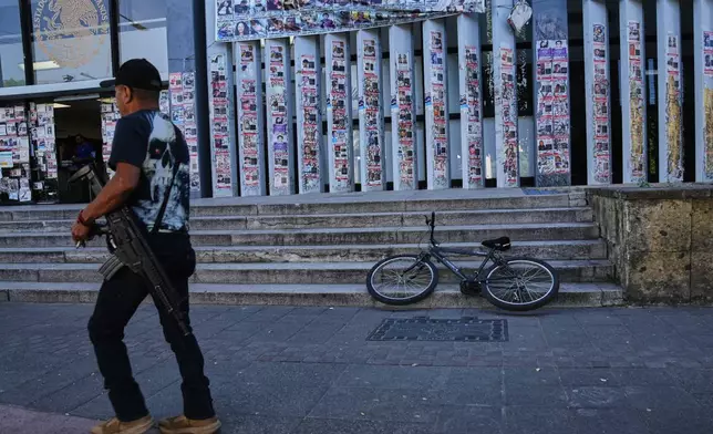 A police officer walks past posters bearing the faces of missing persons in front of the Special Prosecutor's Office for Missing Persons in Guadalajara, Mexico. Wednesday, Feb. 25, 2026. (AP Photo/Marco Ugarte)