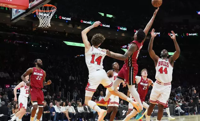 Miami Heat forward Myron Gardner (15) tries to control the ball as Chicago Bulls forward Matas Buzelis (14) and forward Patrick Williams (44) defend during the first half of an NBA basketball game, Saturday, Jan. 31, 2026, in Miami. (AP Photo/Lynne Sladky)