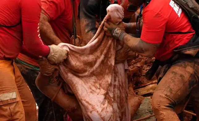 FILE - Firefighters recover a body from the site where homes collapsed during heavy rains and severe flooding in the Parque Burnier neighborhood of Juiz de Fora, Minas Gerais state, Brazil, Feb. 24, 2026. (AP Photo/Silvia Izquierdo, File)