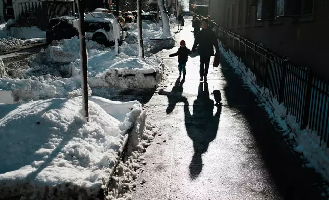 A man walks a boy to school, Tuesday, Feb. 24, 2026, in New York. (AP Photo/Eduardo Munoz Alvarez)