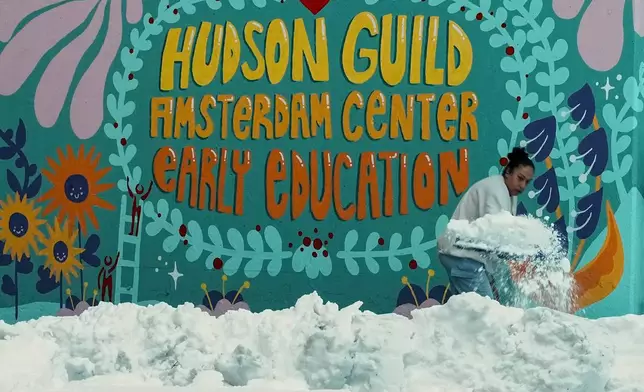 A woman clears snow from a walk outside a preschool, Tuesday, Feb. 24, 2026, in New York. (AP Photo/Eduardo Munoz Alvarez)