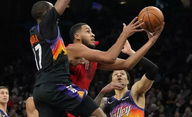 Portland Trail Blazers forward Kris Murray, center, drives between Phoenix Suns guard Jamaree Bouyea (17) and guard Amir Coffey, right, during the first half of an NBA basketball game, Sunday, Feb. 22, 2026, in Phoenix. (AP Photo/Rick Scuteri)