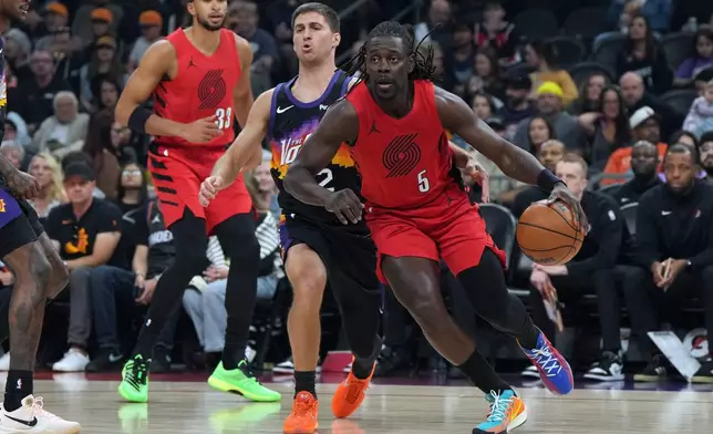 Portland Trail Blazers guard Jrue Holiday (5) drives past Phoenix Suns guard Collin Gillespie, center left, during the first half of an NBA basketball game, Sunday, Feb. 22, 2026, in Phoenix. (AP Photo/Rick Scuteri)
