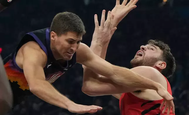 Portland Trail Blazers center Donovan Clingan, right, is fouled by Phoenix Suns guard Collin Gillespie, left, during the first half of an NBA basketball game, Sunday, Feb. 22, 2026, in Phoenix. (AP Photo/Rick Scuteri)