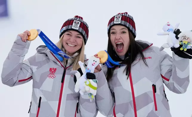Austria's Ariane Raedler, left, and teammate Austria's Katharina Huber show their gold medals in an alpine ski, women's team combined race, at the 2026 Winter Olympics, in Cortina d'Ampezzo, Italy, Tuesday, Feb. 10, 2026. (AP Photo/Andy Wong)