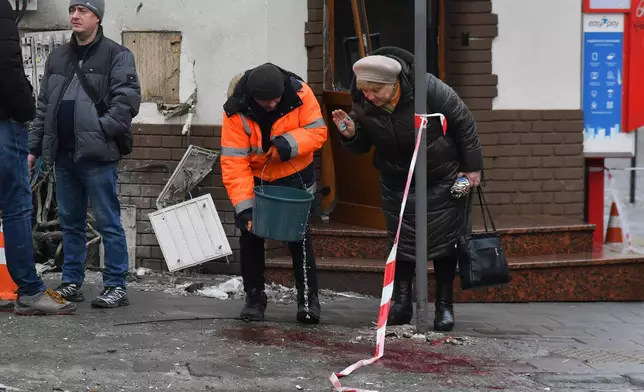 A municipal worker tries to wipe away bloodstains at the site of what authorities are describing as a "terrorist' attack" in central Lviv, Ukraine, Sunday, Feb. 22, 2026. (AP Photo/Mykola Tys)