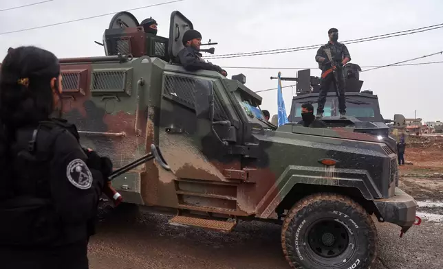 Kurdish-led Syrian Democratic Forces (SDF) soldiers, left and right, stand along the road as vehicles carrying a contingent of Syria's Interior Ministry security forces arrive to implement an agreement with the SDF aimed at stabilizing a ceasefire in al-Hassakeh, eastern Syria, Monday, Feb. 2, 2026. (AP Photo/Baderkhan Ahmad)