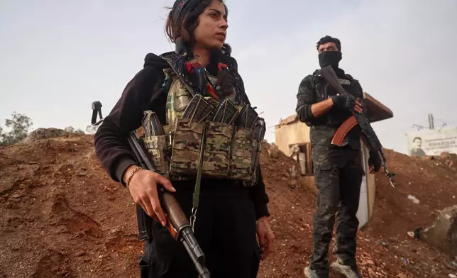 Kurdish-led Syrian Democratic Forces (SDF) combatants look on as a contingent of Syria's Interior Ministry security forces arrive to implement an agreement aimed at stabilizing a ceasefire in al-Hassakeh, eastern Syria, Monday, Feb. 2, 2026. (AP Photo/Baderkhan Ahmad)