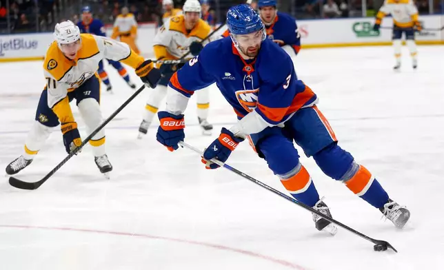 New York Islanders defenseman Adam Pelech, right, controls the puck in front of Nashville Predators forward Matthew Wood during the first period of an NHL hockey game Saturday, Jan. 31, 2026, in Elmont, N.Y. (AP Photo/John Munson)