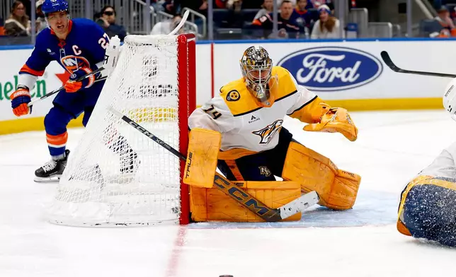 Nashville Predators goalie Juuse Saros, right, keeps his eye on the puck as New York Islanders forward Anders Lee skates behind the net during the second period of an NHL hockey game Saturday, Jan. 31, 2026, in Elmont, N.Y. (AP Photo/John Munson)