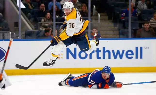 Nashville Predators forward Cole Smith (36) leaps over New York Islanders defenseman Tony DeAngelo (77) during the first period of an NHL hockey game Saturday, Jan. 31, 2026, in Elmont, N.Y. (AP Photo/John Munson)