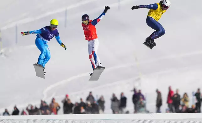 From left, Italy's Michela Moioli (6-2), France's Lea Casta (1-2) and Britain's Charlotte Bankes (13-2) compete during the mixed team snowboard cross finals at the 2026 Winter Olympics, in Livigno, Italy, Sunday, Feb. 15, 2026. (AP Photo/Lindsey Wasson)