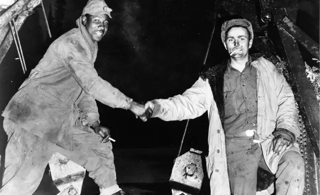 FILE - This Oct. 25, 1942, photo provided by the U.S. Army Corps of Engineers Office of History, shows Corporal Refines Slims, Jr., left, and Private Alfred Jalufka shaking hands at the, "Meeting of Bulldozers," for the ALCAN Highway in the Yukon Territory in Beaver Creek, Alaska. (U.S. Army Corps of Engineers Office of History via AP, File)