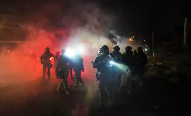 FILE - Law enforcement officers stand amid tear gas at the scene of a reported shooting in Minneapolis, Jan. 14, 2026. (AP Photo/Adam Gray, File)
