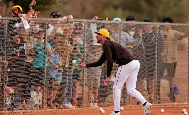 San Diego Padres center fielder Jackson Merrill tosses a ball to fans during spring training baseball practice Monday, Feb. 16, 2026, in Peoria, Ariz. (AP Photo/Charlie Riedel)