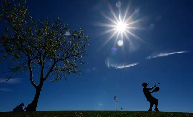 Logan Eaton, age 9, plays catch in the outfield before a spring training baseball game between the Texas Rangers and the Colorado Rockies, Sunday, Feb. 22, 2026, in Surprise, Ariz. (AP Photo/Charlie Riedel)