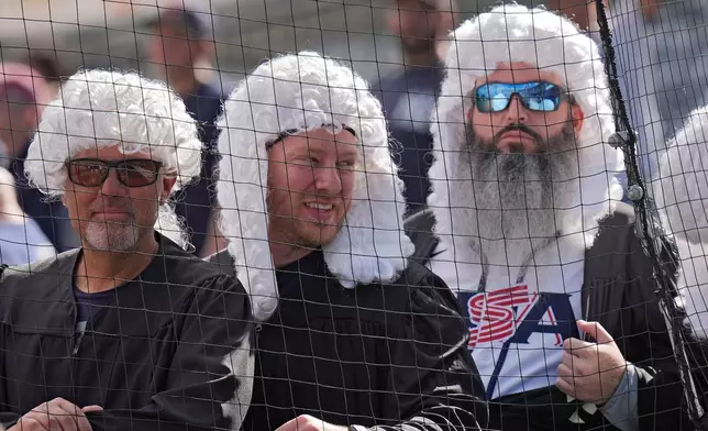 New York Yankees fans, wearing powdered judge's wigs, watch Aaron Judge take batting practice during a spring training baseball workout Monday, Feb. 16, 2026, in Tampa, Fla. (AP Photo/Chris O'Meara)