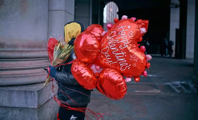 FILE - A man walks holding flowers and balloons on Valentine's Day, Friday, Feb. 14, 2025, in New York. (AP Photo/Andres Kudacki, File)