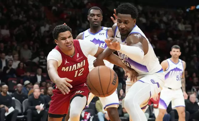 Miami Heat guard Dru Smith (12) and Utah Jazz forward Jaren Jackson Jr. (20) go after a loose ball during the first half of an NBA basketball game Monday, Feb. 9, 2026, in Miami. (AP Photo/Marta Lavandier)