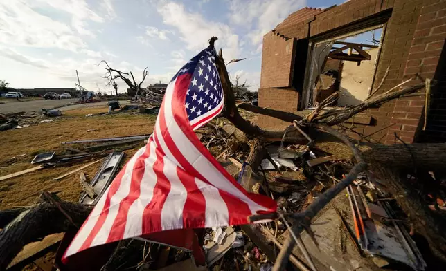 FILE - An American flag flies amidst debris of destroyed homes, in the aftermath of tornadoes that tore through the region, in Mayfield, Ky., Dec. 14, 2021. (AP Photo/Gerald Herbert, File)