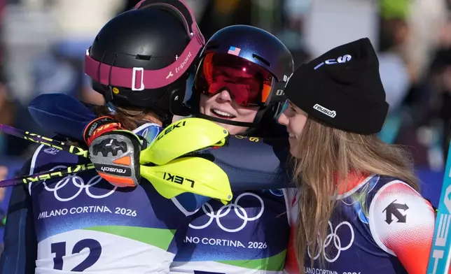 United States' Mikaela Shiffrin, center, winner of an alpine ski, women's slalom race, is congratulated by second-placed Switzerland's Camille Rast, right, and third-placed Sweden's Anna Swenn Larsson, at the 2026 Winter Olympics, in Cortina d'Ampezzo, Italy, Wednesday, Feb. 18, 2026. (AP Photo/Jacquelyn Martin)