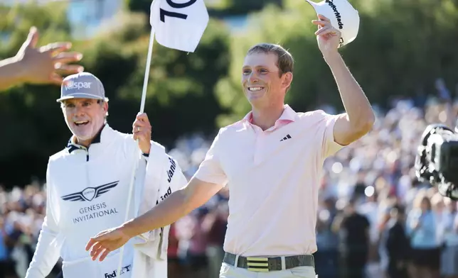 Jacob Bridgeman smiles next to caddie GW Cable after winning the Genesis Invitational golf tournament at Riviera Country Club, Sunday, Feb. 22, 2026, in the Pacific Palisades area of Los Angeles. (AP Photo/Caroline Brehman)