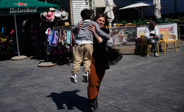 People rush to take shelter as warning sirens sound following missile fired towards Israel, in Tel Aviv, Israel, Saturday, Feb. 28, 2026. (AP Photo/Ohad Zwigenberg)