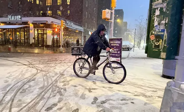 A man rides a bicycle in the beginning of an intense snowstorm by 20th Street and First Avenue, Sunday, Feb. 22, 2026, in New York. (AP Photo/Pamela Hassell)