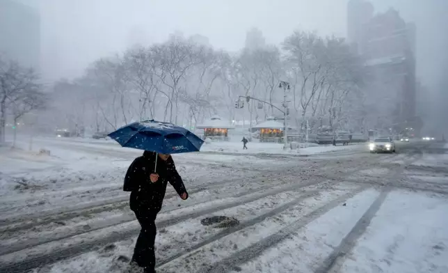 A pedestrian crosses a snow-covered Sixth Avenue near Bryant Park, Monday, Feb. 23, 2026, in New York. (AP Photo/Seth Wenig)