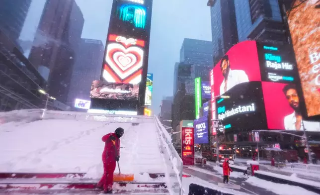 A worker with the Times Square Alliance sanitation crew clears snow from the Red Stairs in Times Square, Monday, Feb. 23, 2026, in New York. (AP Photo/Seth Wenig)