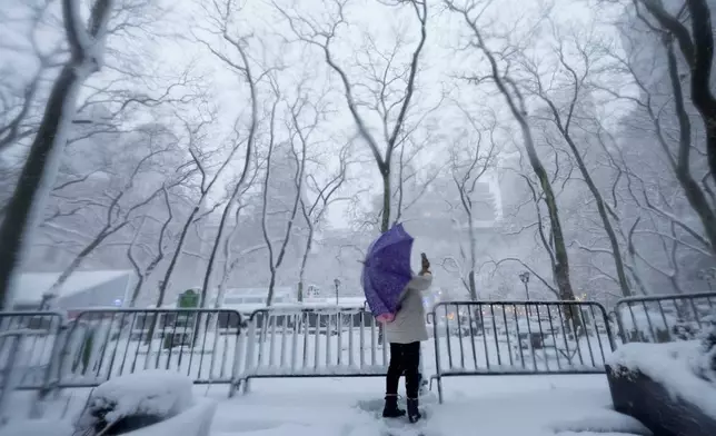 A woman stops to take photos of Bryant Park in the snow, Monday, Feb. 23, 2026, in New York. (AP Photo/Seth Wenig)