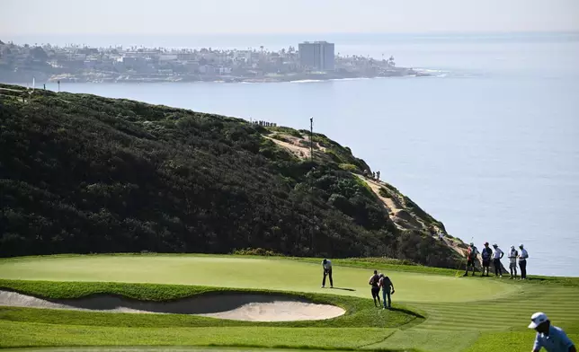 Justin Rose, of England, at right, putts on the third green of the South Course at Torrey Pines during the third round of the Farmers Insurance Open golf tournament Saturday, Jan. 31, 2026, in San Diego. (AP Photo/Denis Poroy)