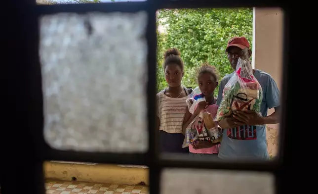 Guillermo Beltran, a recipient of Mexican humanitarian assistance, poses for a photo with his daughters Chanely, left and Chanela, holding his donated items at their home in Havana, Cuba, Thursday, Feb. 19, 2026. (AP Photo/Ramon Espinosa)